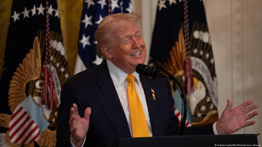 Donald Trump habla ante un micrófono con banderas de Estados Unidos al fondo
