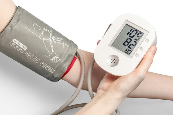 Persona midiendo la presión arterial en el brazo correcto con un tensiómetro en casa