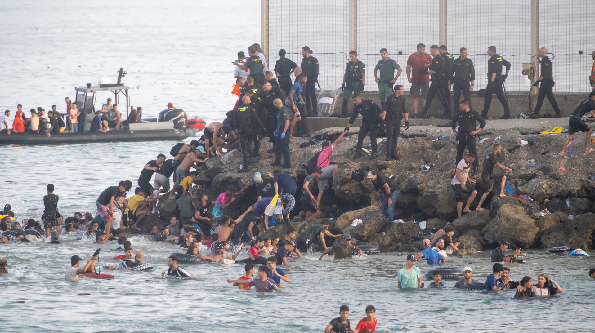 Migrantes en Ceuta intentando cruzar la frontera mientras guardias fronterizos vigilaban el perímetro
