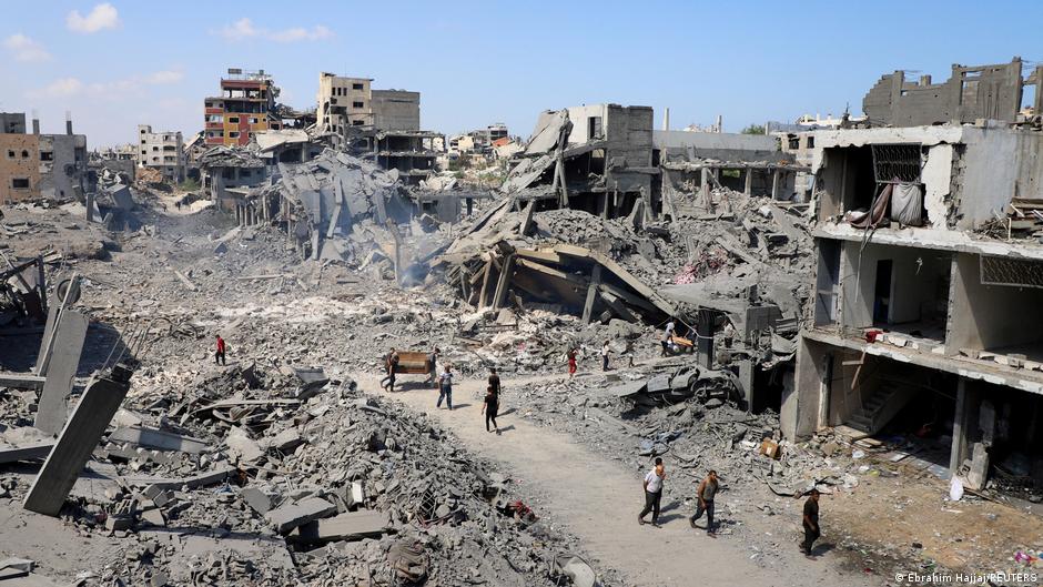 Columna de humo tras un ataque israelí en Gaza con edificios destruidos en el fondo
