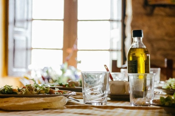 Botella de aceite de oliva junto a aceitunas frescas, errores comunes al consumirlo