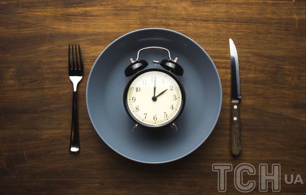 Persona comiendo a deshoras con reloj en la mesa que muestra un horario de comidas irregular