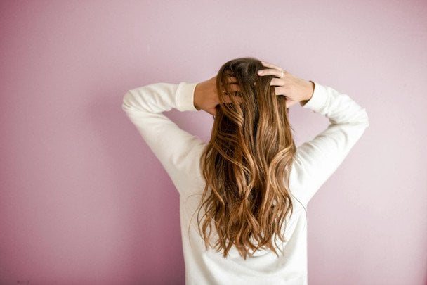 Mujer aplicando rutina de cuidado cabello otoño con productos hidratantes entre hojas secas